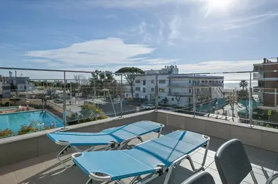 a balcony with blue chairs and a swimming pool at Apartamentos Castellmar in Castelldefels