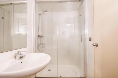 a white bathroom with a sink and a shower at Apartamentos Castellmar in Castelldefels