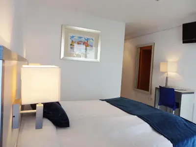 a bedroom with a large white bed and a desk at Parrots Sitges Hotel in Sitges