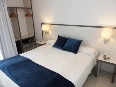 a hotel room with two beds with blue pillows at Parrots Sitges Hotel in Sitges