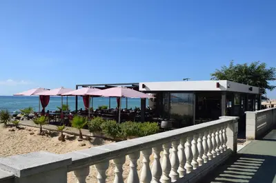 a restaurant on the beach with tables and umbrellas at Apartamentos Les Barbes in Caldes d'Estrac