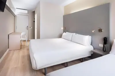 a bedroom with a large white bed and a table at B&B HOTEL Barcelona Mollet in Mollet del Vallès