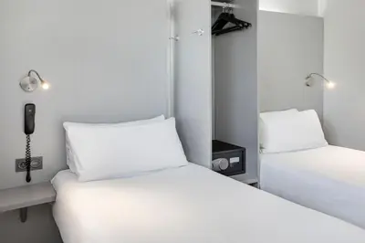 a room with two beds and a phone on the wall at B&B HOTEL Barcelona Granollers in Les Franqueses del Vallès