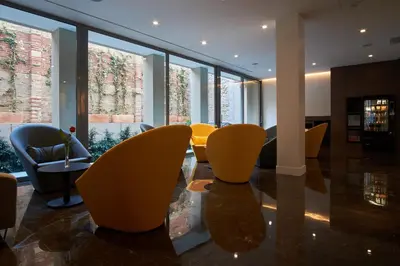 a lobby with yellow chairs and tables and large windows at Chi in Barcelona