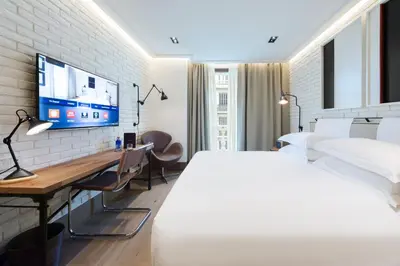 a bedroom with a bed and a desk and a tv at The Corner Hotel in Barcelona