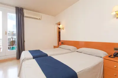 a hotel room with two beds and a window at Hotel Everest in Barcelona