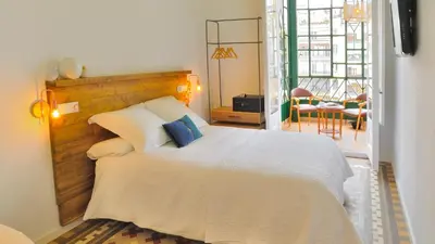 a bedroom with a large white bed and a balcony at Hostal Girona in Barcelona