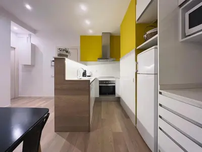 a kitchen with white and yellow cabinets and a black table at Stay U-nique Apartments Sants in Barcelona