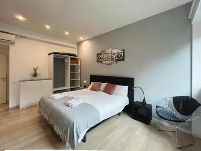 a bedroom with a large white bed and a chair at Stay U-nique Apartments Sants in Barcelona
