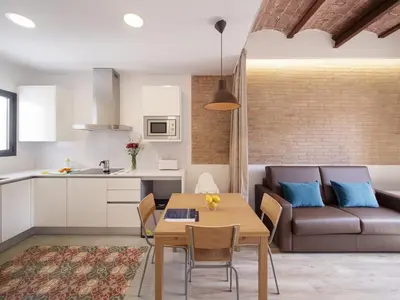a kitchen and living room with a table and a couch at Hotel Sagrada Familia Apartments in Barcelona