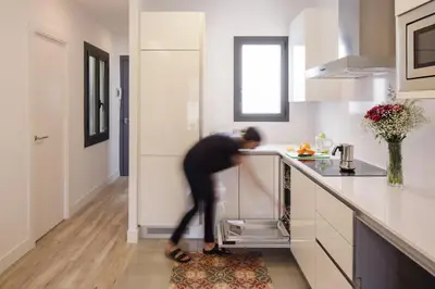 a man in a kitchen reaching into a dishwasher at Hotel Sagrada Familia Apartments in Barcelona