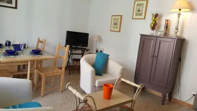 a living room with a chair and a table and a tv at Apartamento Hector en Sitges in Sitges