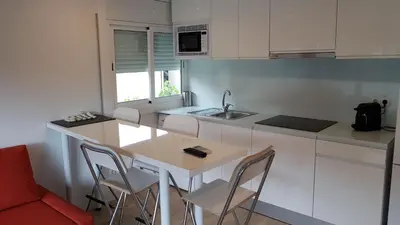 a kitchen with white cabinets and a table and chairs at Castelldefels Playa in Castelldefels