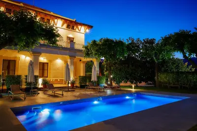 a swimming pool in front of a house at night at Hotel Arrey Alella in Alella