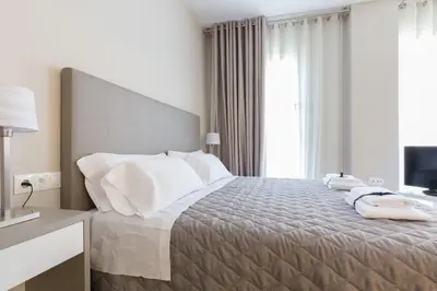 a bedroom with a bed with white pillows and a television at Flateli 430 BCN in Barcelona