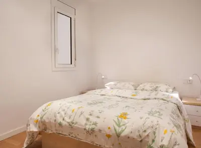 a white bedroom with a bed with a floral bedspread at Authentic flat2 in Poble sec - Paralelo in Barcelona
