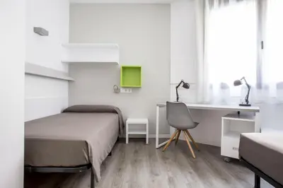 a bedroom with two beds and a desk and a chair at Residencia Universitaria Resa Barcelona Diagonal in Barcelona