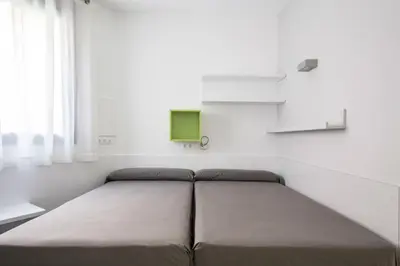 a bed in a white room with a green monitor at Residencia Universitaria Resa Barcelona Diagonal in Barcelona