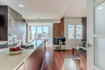 a kitchen with a counter and a living room at Enjoybcn Fira Apartment in Barcelona