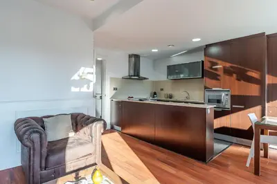 a living room with a chair and a kitchen at Enjoybcn Fira Apartment in Barcelona