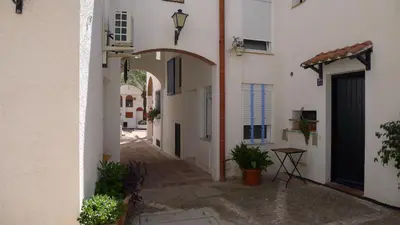 an alley with white buildings and an archway at Mini Apartamento Port Aiguadolç in Sitges