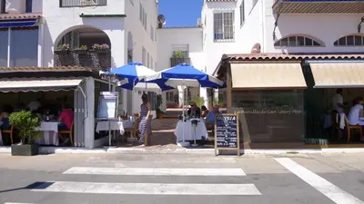 a group of tables with blue umbrellas in a street at Mini Apartamento Port Aiguadolç in Sitges