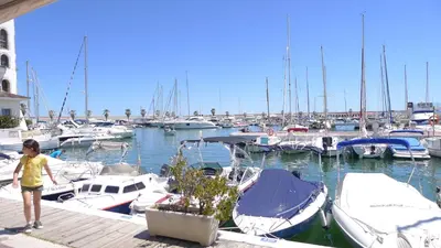 a boy standing on a dock with boats in a marina at Mini Apartamento Port Aiguadolç in Sitges