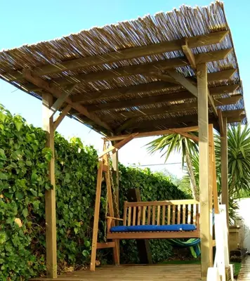 a wooden bench under a wooden pergola at Casa Garcia in Sitges