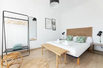 a white bedroom with a bed and a table at Housalia Familia Rossellon in Barcelona