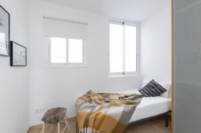 a white room with a couch and two windows at Housalia Familia Rossellon in Barcelona