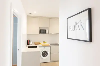 a kitchen with white cabinets and a washer and dryer at Housalia Familia Rossellon in Barcelona