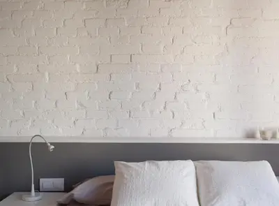 a white brick wall behind a bed with a lamp at Napoles · Modernist flat close to Sagrada Familia in Barcelona