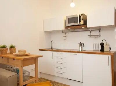 a kitchen with white cabinets and a microwave at Borrell · Near ramblas in Barcelona