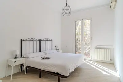 a white bedroom with a large bed and a window at 2215 - AB Calabria Apartment in Barcelona