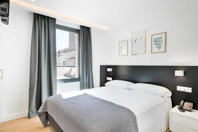 a bedroom with a white bed and a window at Murmuri Residence Mercader in Barcelona