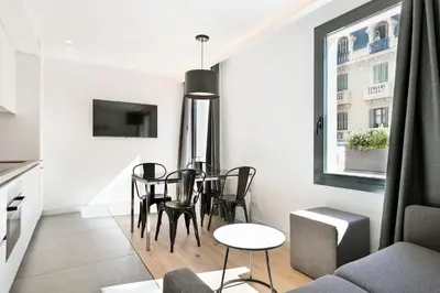a dining room with a table and chairs and a window at Murmuri Residence Mercader in Barcelona