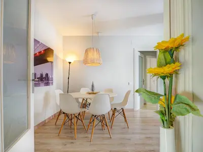 a dining room with a table and chairs and a vase with yellow flowers at Amazing Terrace in the Center by Hello Homes Sitges in Sitges