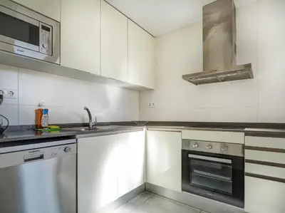 a kitchen with white cabinets and a sink and a stove at Amazing Terrace in the Center by Hello Homes Sitges in Sitges