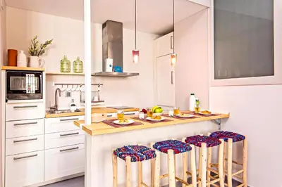 a kitchen with white cabinets and a counter with stools at Sweett - Raco in Barcelona