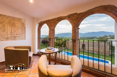 a room with a balcony with a view of a pool at Masia Can Canyes & Spa in San Lorenzo de Hortóns