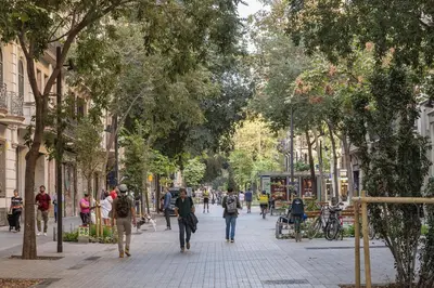 a group of people walking down a street with trees at HoHomes - Luxury Palacete in Barcelona