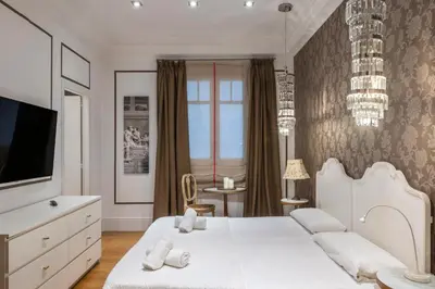 a white bedroom with a bed and a tv at HoHomes - Luxury Palacete in Barcelona