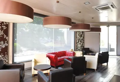 a waiting room with a red couch and chairs at Hotel Els Noguers in Manresa