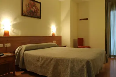 a bedroom with a bed and two lights on the wall at Hotel Flora Parc in Castelldefels
