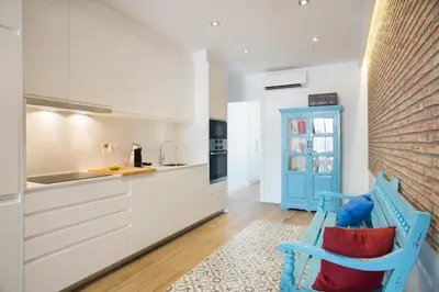 a kitchen with white cabinets and a blue chair at Sweet Home Sitges BY BLAUSITGES in Sitges