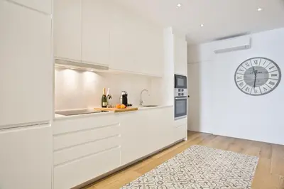 a kitchen with white cabinets and a clock on the wall at Sweet Home Sitges BY BLAUSITGES in Sitges