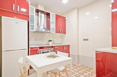 a kitchen with a white table and red cabinets at Citytrip Palau de la Música in Barcelona