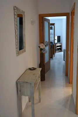 a hallway with a wooden table and a vase with flowers at Apartamento Flavia I Espalter in Sitges