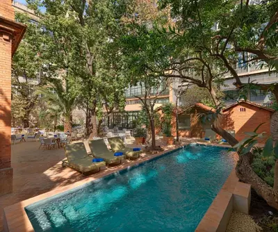 a swimming pool with lounge chairs and trees in a yard at H10 Casa Mimosa 4* Sup in Barcelona