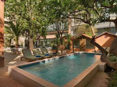 a swimming pool in a courtyard with chairs and trees at H10 Casa Mimosa 4* Sup in Barcelona